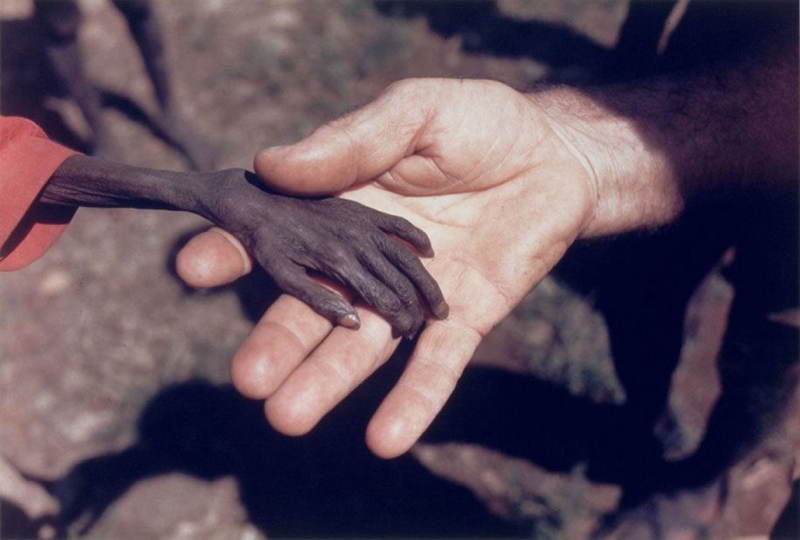 Misionár drží za ruku hladujúceho chlapca v Ugande. Rok 1980.