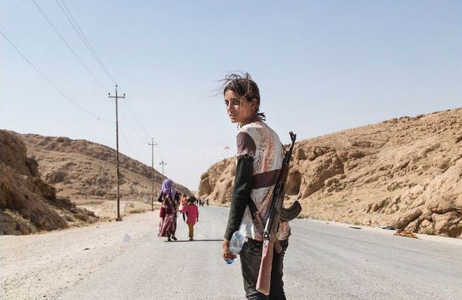 Yezidské dievča nesie pušku aby ochránilo svoju rodinu pred ISIS.