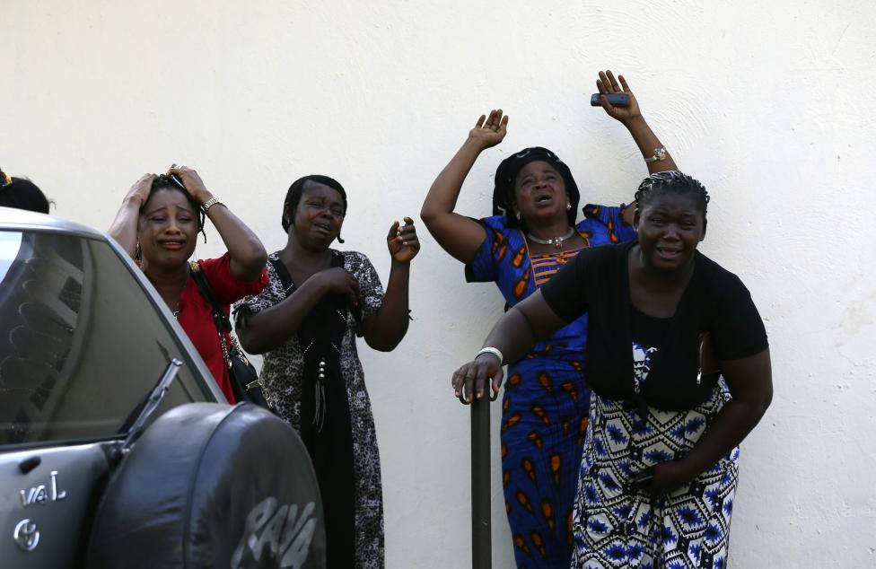 Okoloidúci reagujú na obete výbuchu bomby, ktoré akurát prinášajú do nemocnice. Nigéria, 14.4.2014.