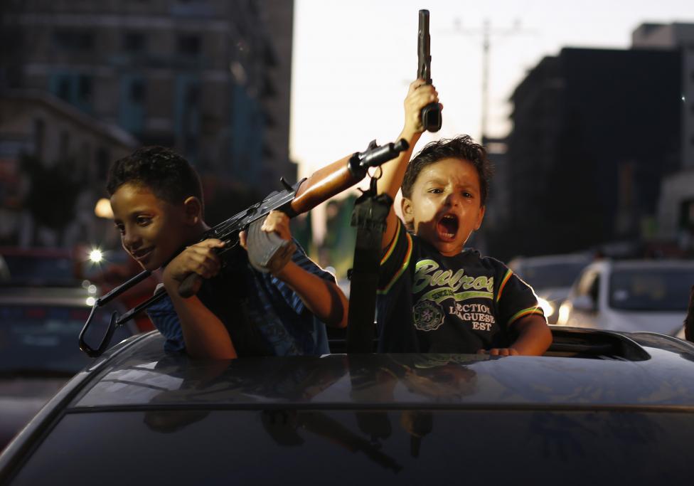 Palestínske deti držia zbrane a oslavujú, po tom, čo im povedali, že vyhrali nad Izraelom. NAsledovalo zastavenie paľby v Gaze. 26.8.2014.