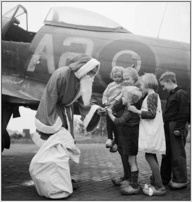 Britský pilot rozdáva holandským deťom potraviny. Nemecko prestalo zásobovať Holandsko jedlom, palivom. (13. december 1944) 