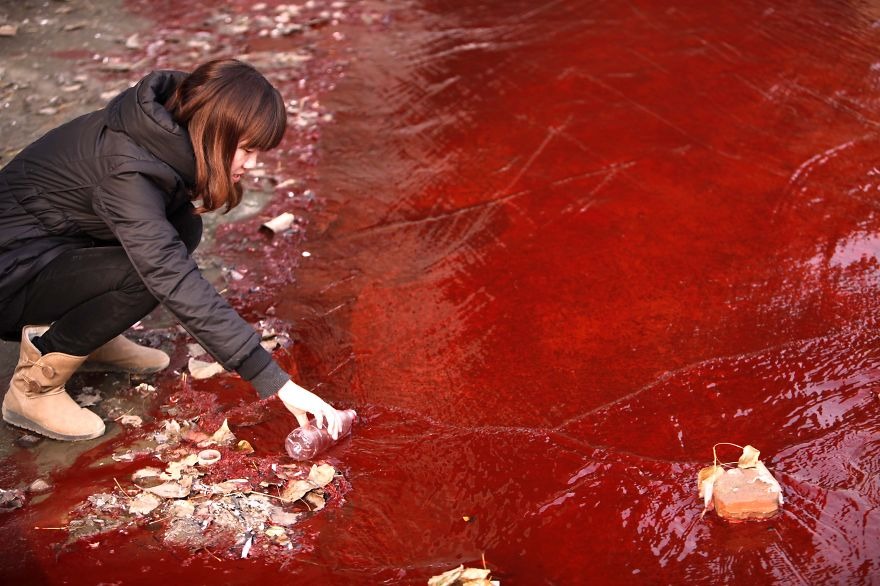 Novinárka berie vzorku znečistenej vody z rieky Jianhe.